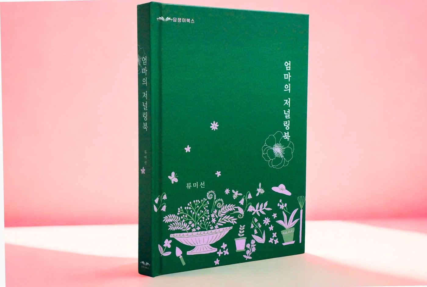 엄마의 저널링북 실물 사진 — 짙은 숲초록 양장 표지에 꽃과 나비 자수 무늬